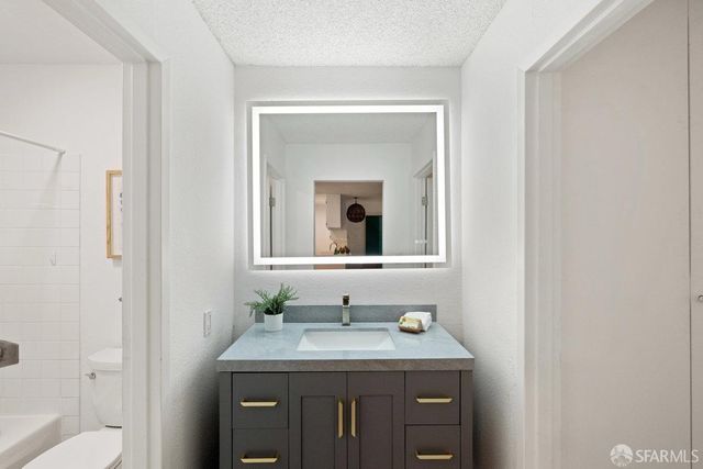 a bathroom with a granite countertop sink a toilet and a mirror