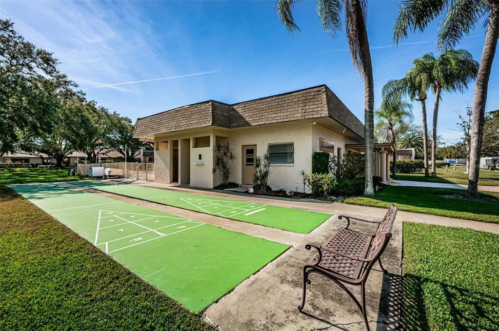 11511 113th Street, Unit 35E Largo, FL 33778 - Photo 60 of 77 a view of a house with a swimming pool and a lawn chairs under a large tree