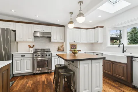 a kitchen with stainless steel appliances a sink a stove a refrigerator cabinets and a center island