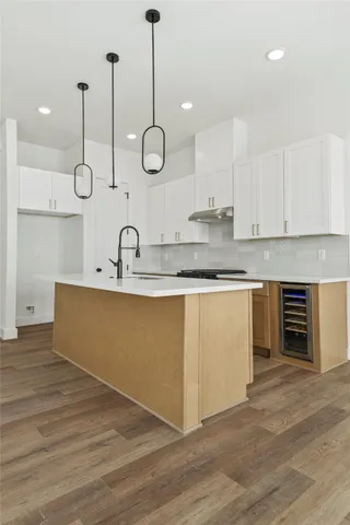 a kitchen with stainless steel appliances granite countertop a sink a stove and a wooden floors