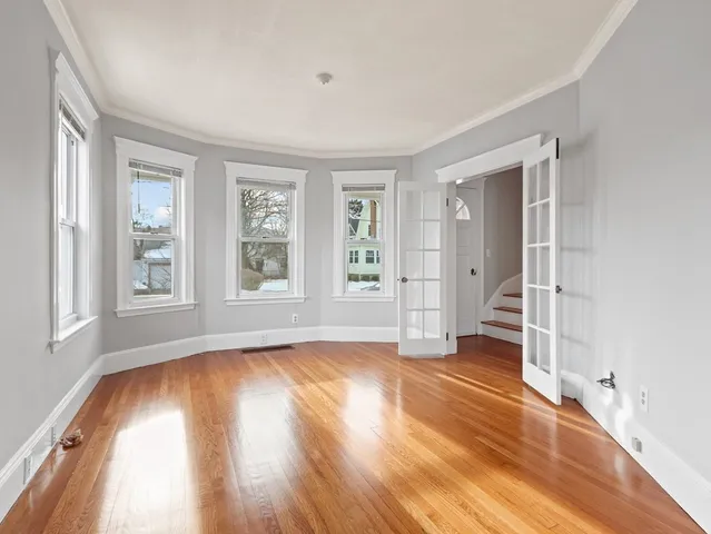 a view of an empty room with wooden floor and a window