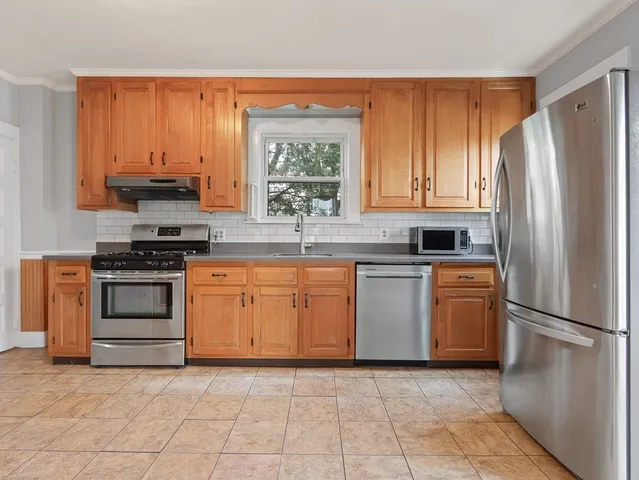 a kitchen with granite countertop a refrigerator stove and cabinets