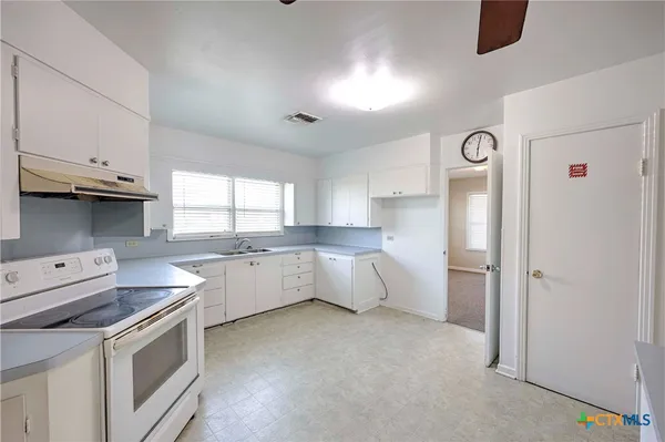 a kitchen that has a lot of white cabinets and stainless steel appliances