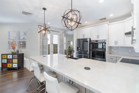 a large kitchen with stainless steel appliances a large center island attached withe living room