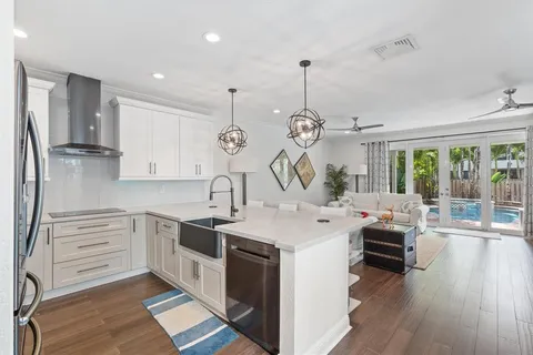 a kitchen with a sink dishwasher a stove and a dining table with wooden floor