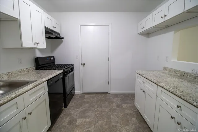 a kitchen with granite countertop white cabinets and a stove