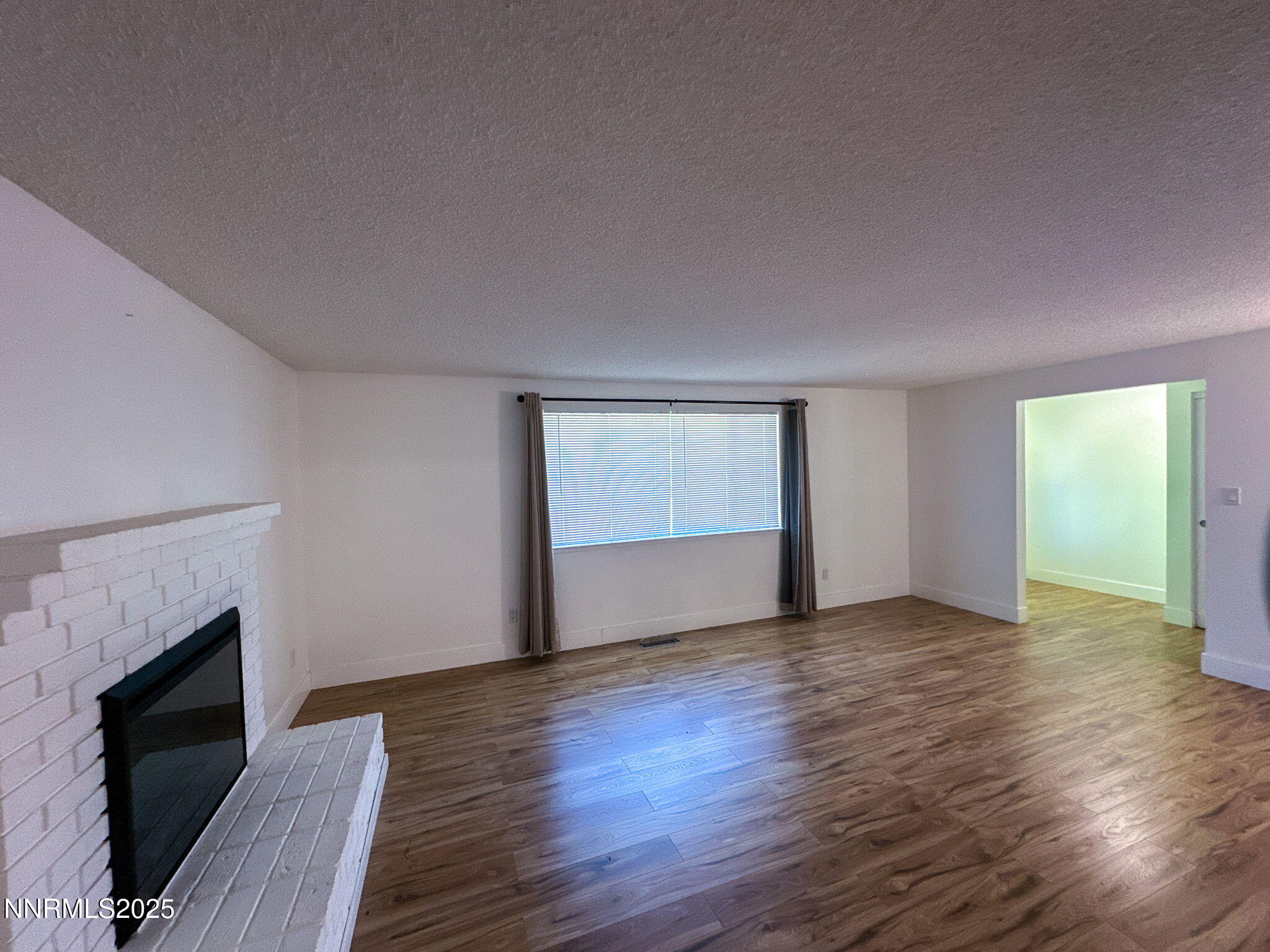 3095 Randolph Drive Reno, NV 89502 - Photo 6 of 20 a view of an empty room with wooden floor fireplace and a window