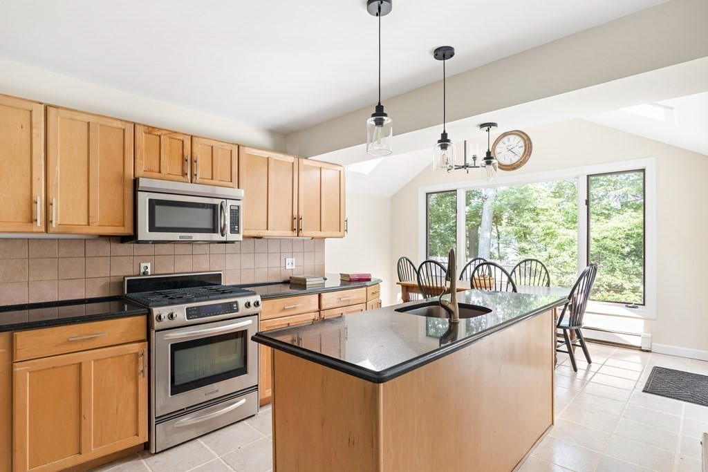 26 Leland Road Brookline, MA 02467 - Photo 8 of 30 a kitchen with stainless steel appliances granite countertop a stove a sink a microwave cabinets and a dining table