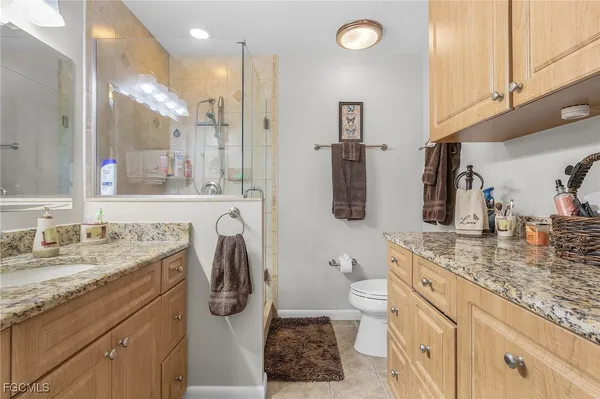a bathroom with a granite countertop sink a toilet a mirror and vanity