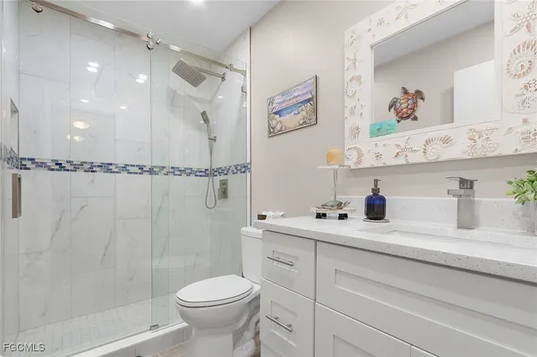 a bathroom with a shower sink vanity mirror and toilet