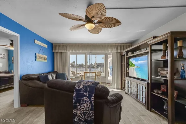 a living room with furniture a flat screen tv and a floor to ceiling window