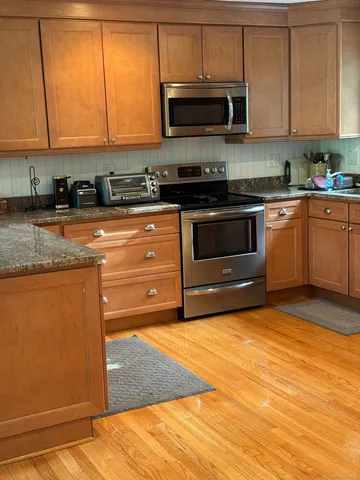 a kitchen with stainless steel appliances granite countertop a stove a sink and a microwave