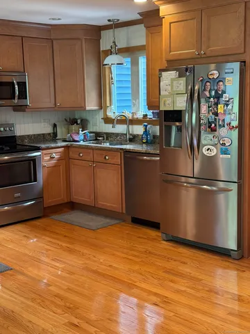 a kitchen with granite countertop stainless steel appliances a stove a sink and a refrigerator