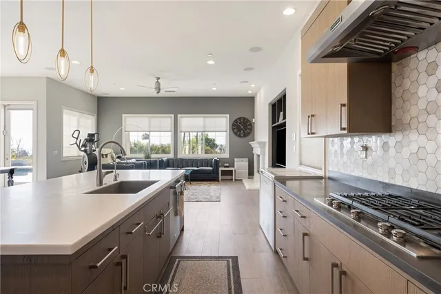 a large kitchen with stainless steel appliances a sink a stove and a wooden floors