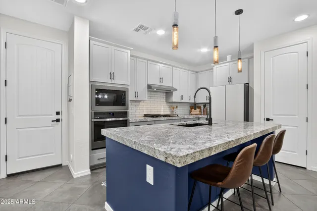 a kitchen with kitchen island granite countertop a table chairs refrigerator and microwave