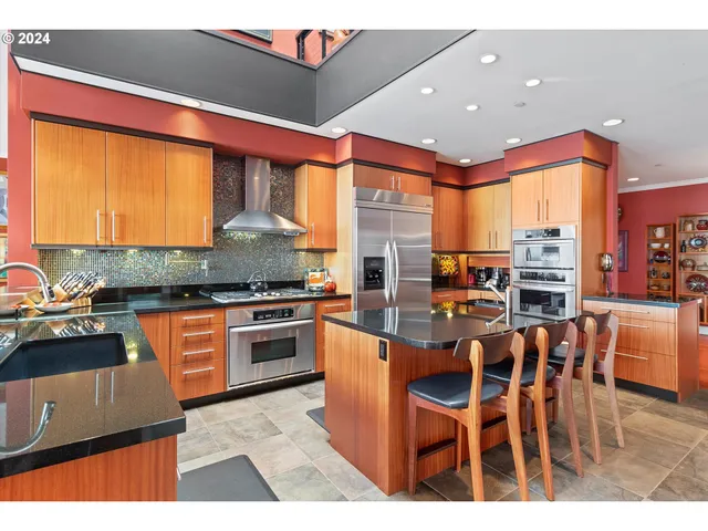 a kitchen with stainless steel appliances granite countertop a stove top oven a sink a dining table and chairs
