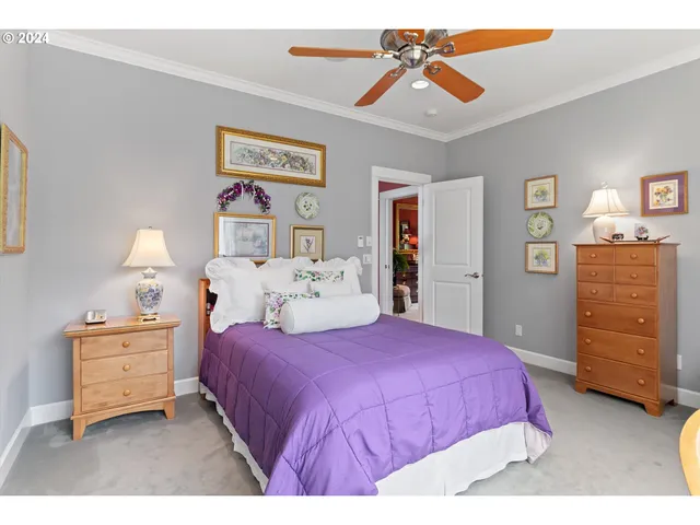 a bedroom with a bed couch chandelier and a large window