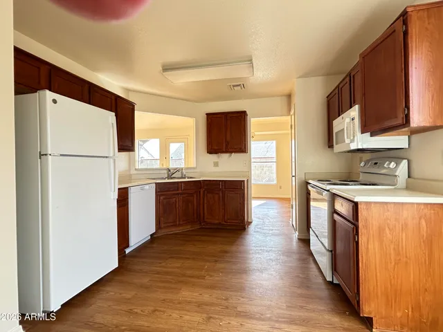 a kitchen with stainless steel appliances granite countertop a refrigerator a sink dishwasher a stove with wooden cabinets and wooden floor