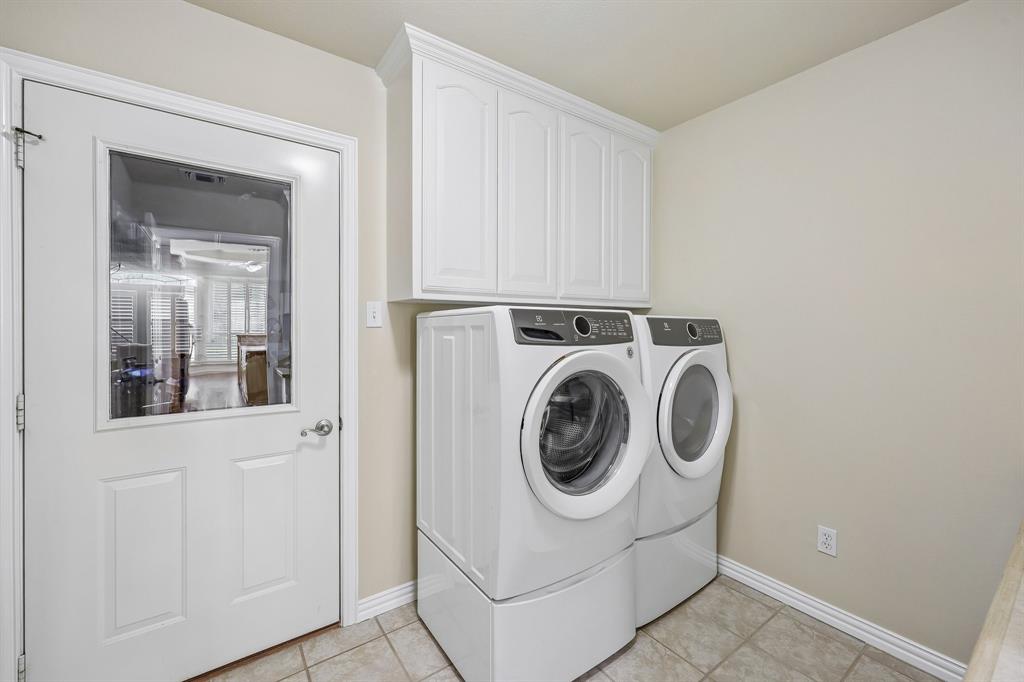 5409 Wedgefield Road Granbury, TX 76049 - Photo 16 of 39 Laundry area featuring tiled flooring, white upper cabinetry, and a white paneled door with a clear glass insert
