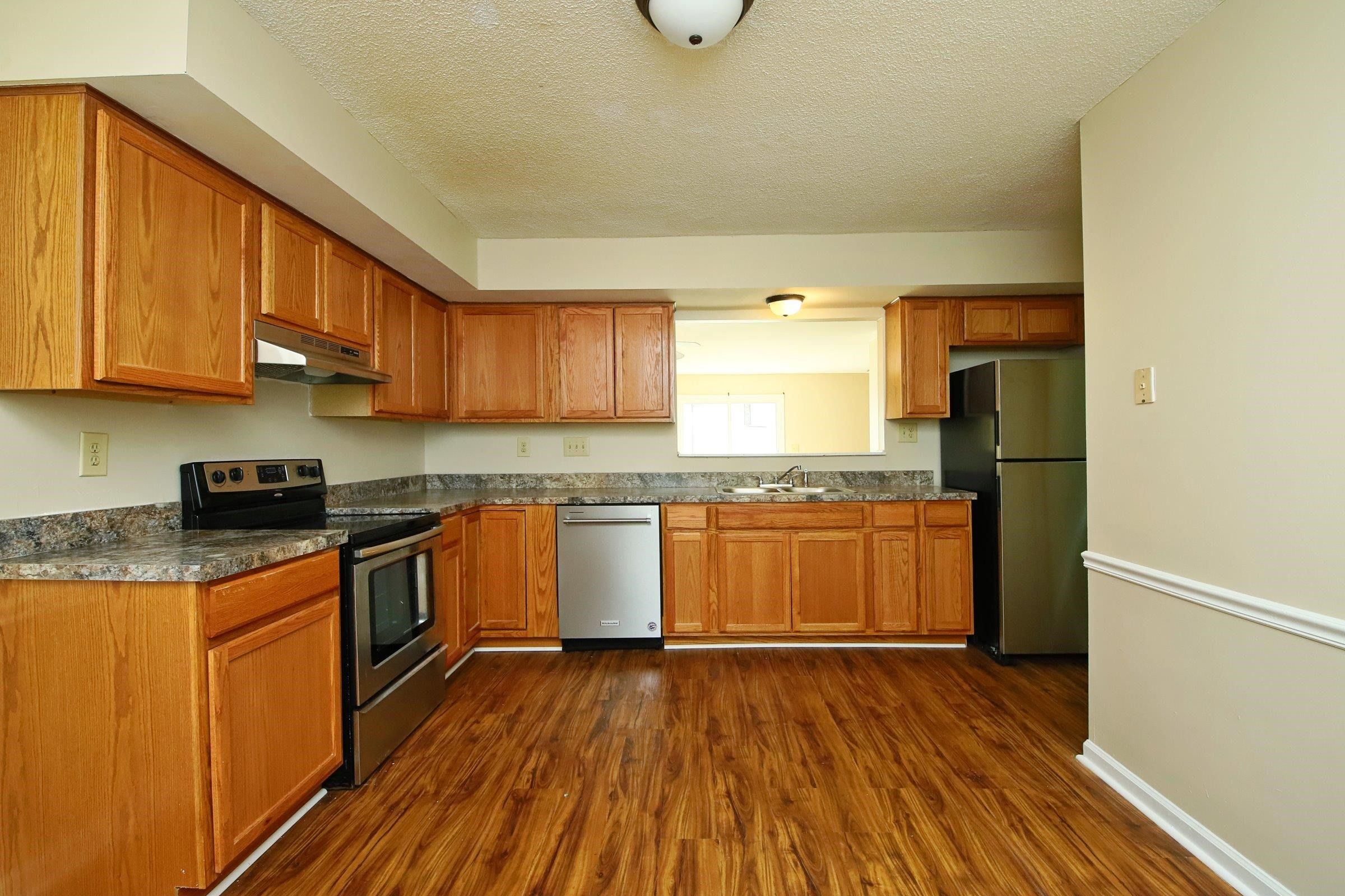1227 Seaton Road, Unit 56 Durham, NC 27713 - Photo 4 of 30 a kitchen with a refrigerator and wooden cabinets