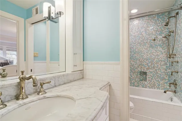 a bathroom with a granite countertop sink a mirror and a bathtub