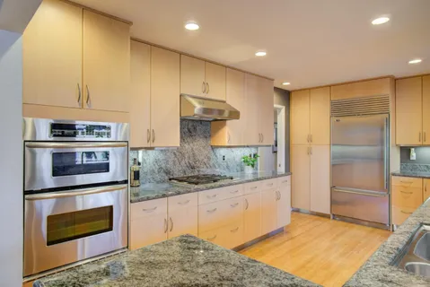 a kitchen with stainless steel appliances granite countertop a stove a refrigerator and a sink