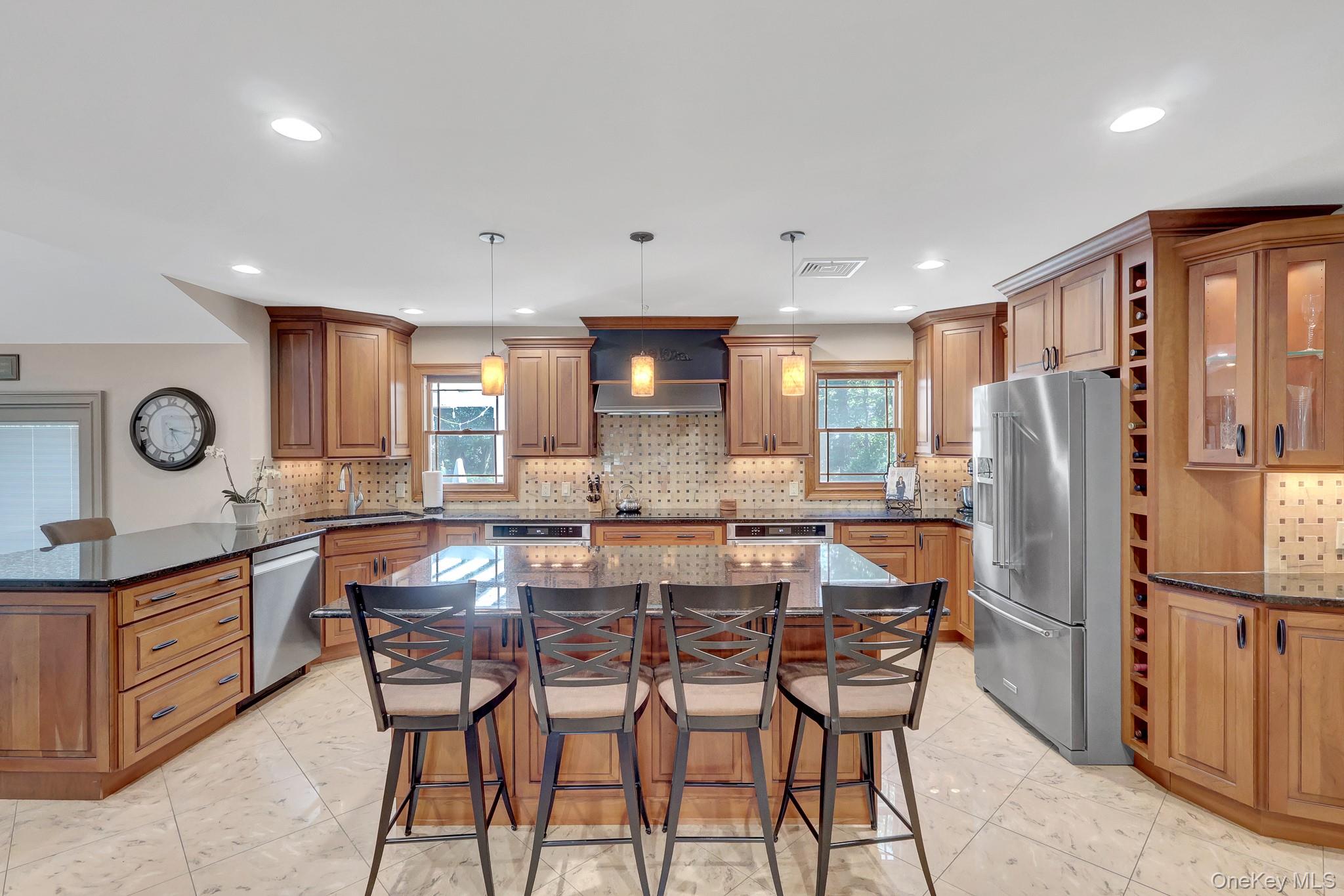 24 Fox Road East Setauket, NY 11733 - Photo 9 of 48 Spacious kitchen featuring an expansive center island with seating, warm wood cabinetry, built in wine rack, dark countertops, stainless steel appliances, and tile flooring