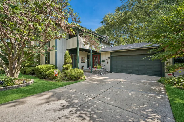a front view of a house with a garden and trees