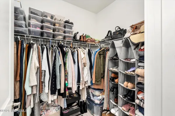 a view of walk in closet with clothes and shoes