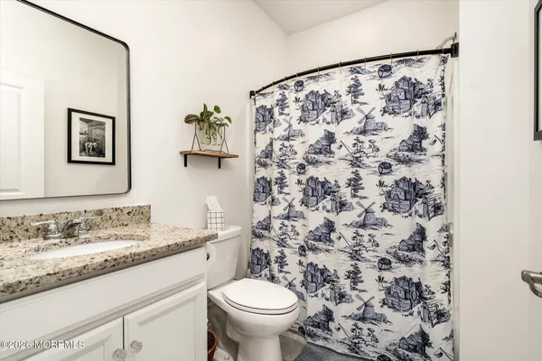 a bathroom with a granite countertop sink a toilet and a mirror