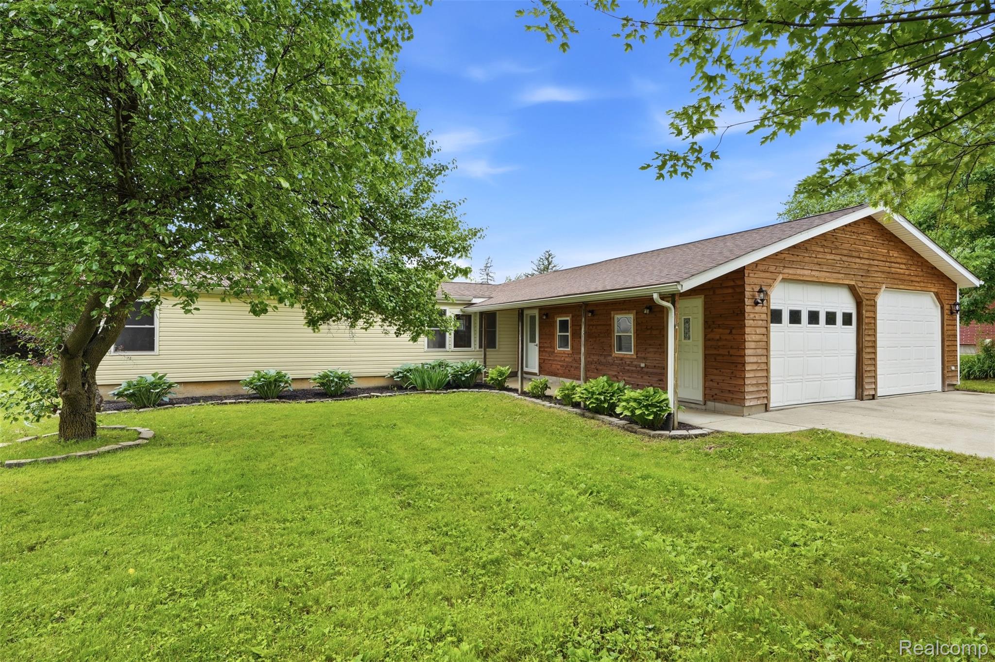 4420 Dublin Road Burton, MI 48529 - Photo 1 of 56 Ranch-style exterior with light yellow siding and a two-car garage featuring wood-look siding and white panel doors