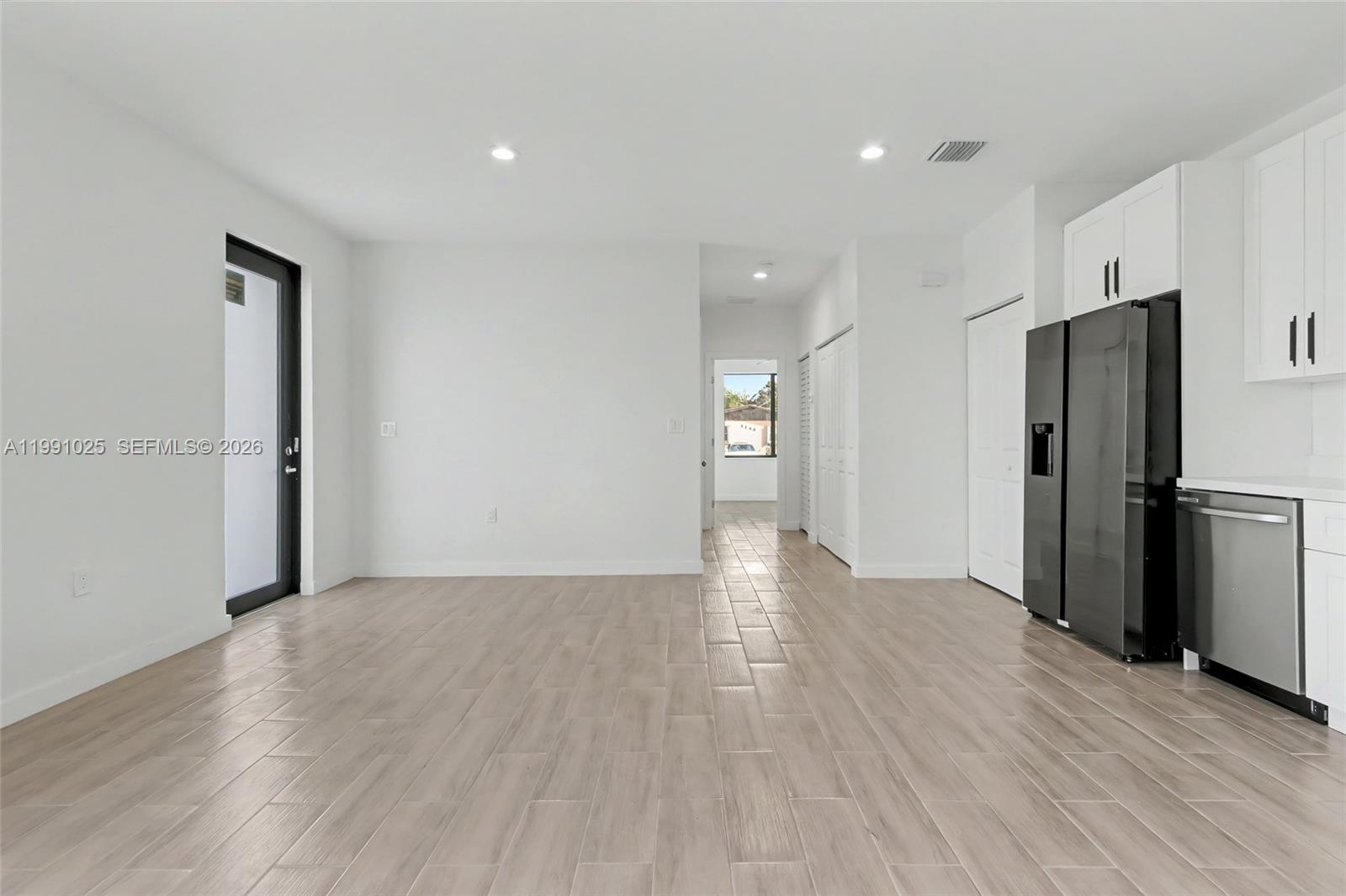 6140 Southwest 39th Street Miramar, FL 33023 - Photo 13 of 40 a view of an empty room with wooden floor and a kitchen
