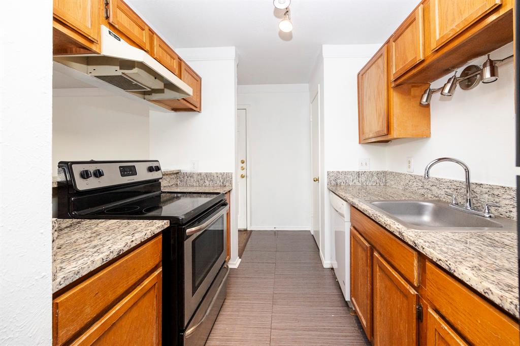 18333 Roehampton Drive, Unit 825 Dallas, TX 75252 - Photo 12 of 23 Galley kitchen featuring wood cabinetry, granite-finish countertops, stainless steel appliances, a stainless steel sink, and tile flooring