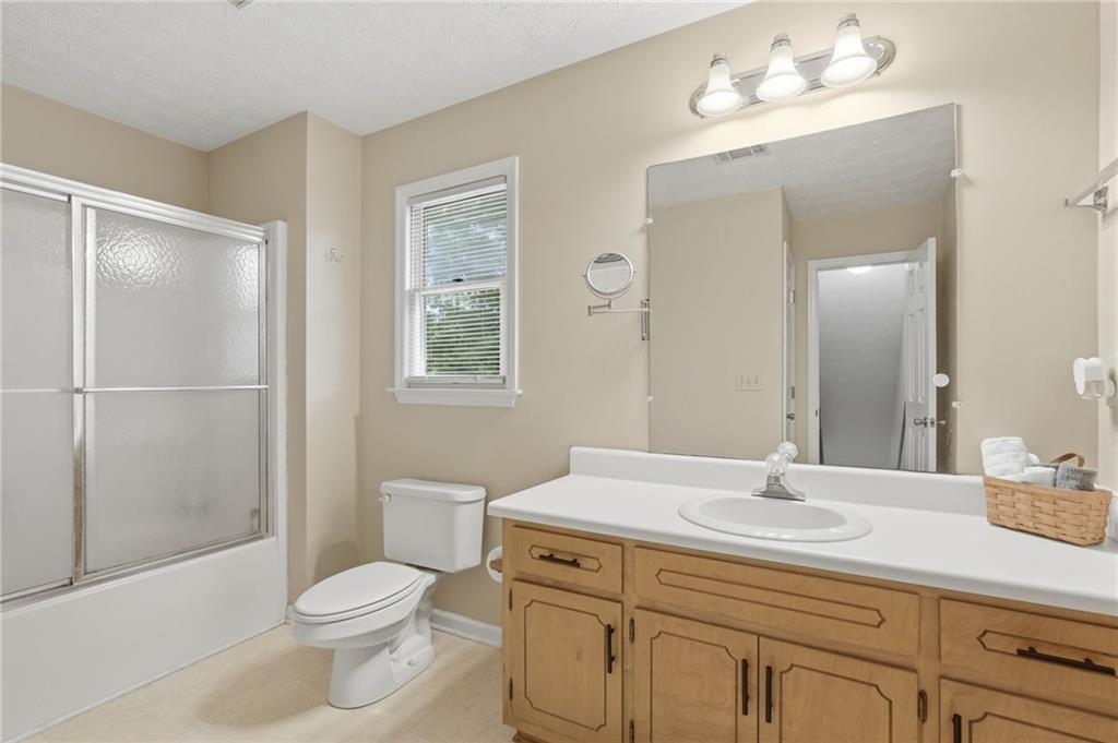 4891 Bill Cheek Road Auburn, GA 30011 - Photo 44 of 99 a bathroom with a toilet a sink a mirror a shower a vanity and window