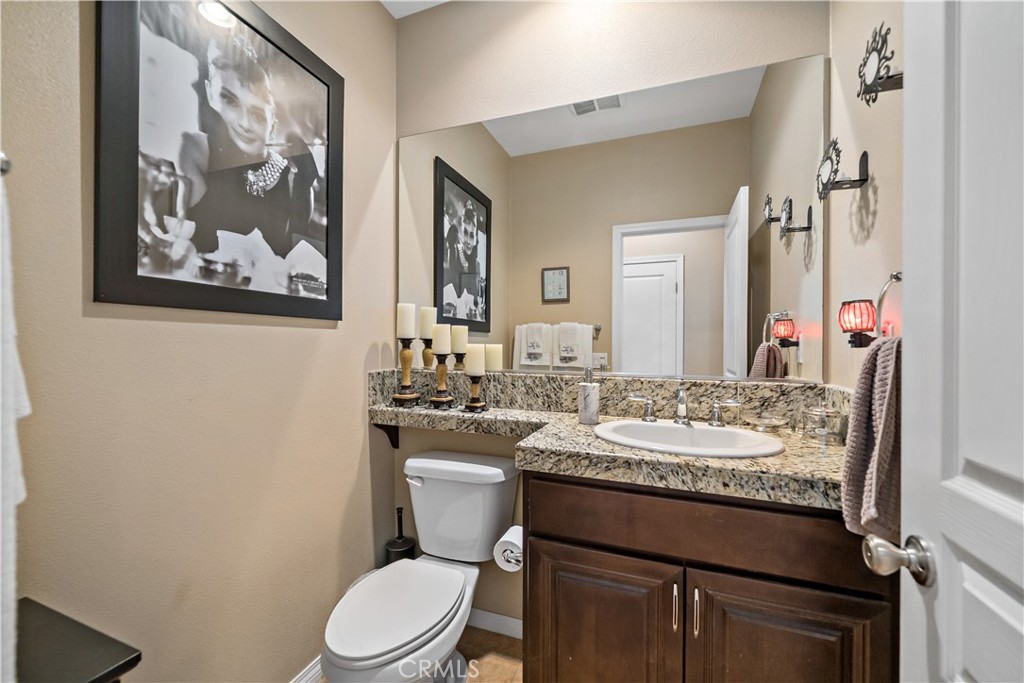29009 Smooth Sailing Court Menifee, CA 92585 - Photo 32 of 62 a bathroom with a granite countertop toilet a sink and a mirror