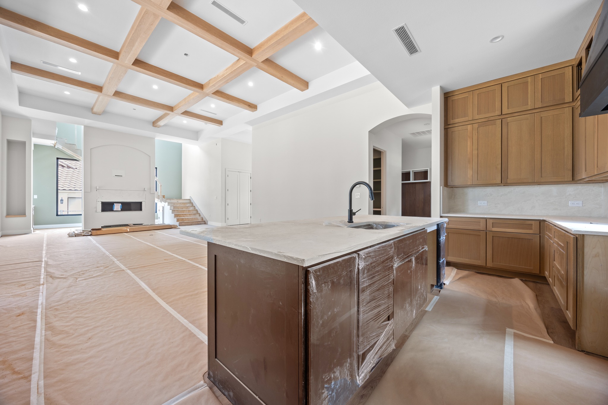 903 Flint Ridge Trail Georgetown, TX 78628 - Photo 10 of 39 Spacious kitchen island with an integrated sink and matte black faucet, surrounded by wood cabinetry, light countertops, and a white tile backsplash
