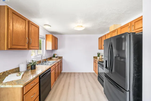 a kitchen with granite countertop stainless steel appliances a refrigerator stove top oven and sink