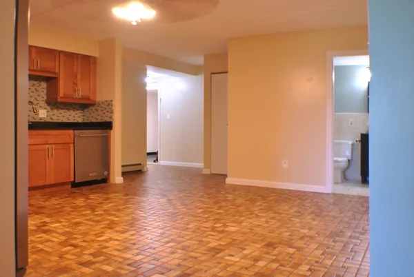 a view of an empty room with window and wooden floor