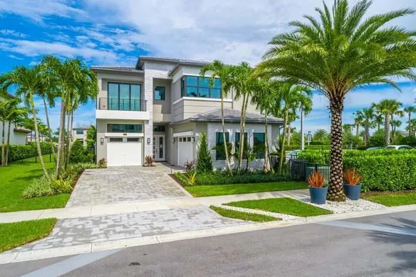 a view of a house with a yard and palm trees
