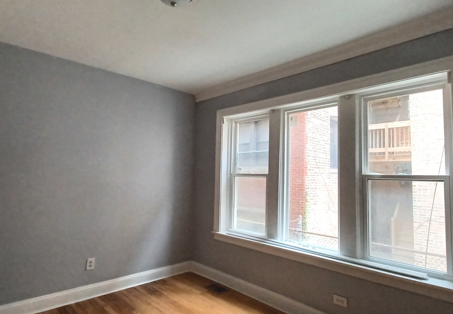 7307 South Bennett Avenue, Unit 1 Chicago, IL 60649 - Photo 4 of 9 an empty room with wooden floor and windows