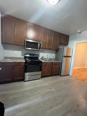 a kitchen with stainless steel appliances granite countertop wooden cabinets a stove a sink and a refrigerator