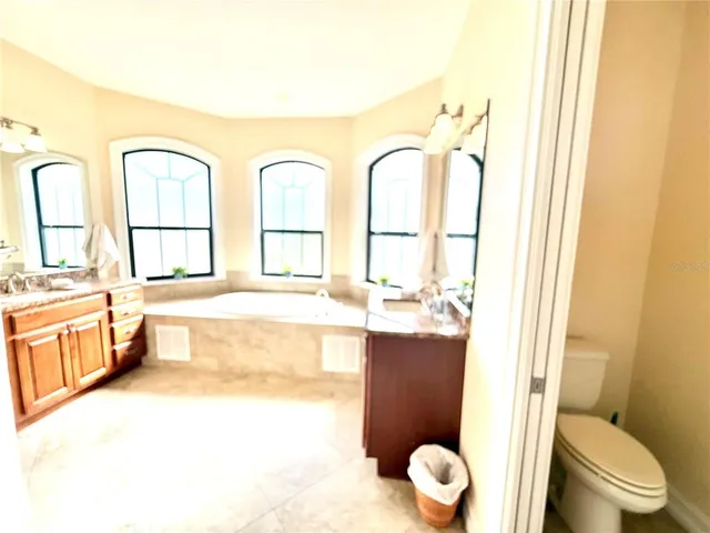 a spacious bathroom with a granite countertop sink a toilet and a bathtub