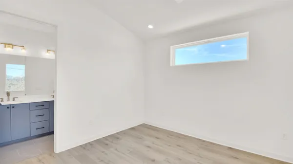 an empty room with wooden floor and fan