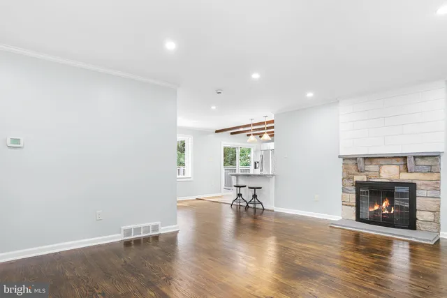 a view of an empty room with fire place and wooden floor