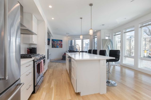 a large kitchen with stainless steel appliances a large center island attached withe living room