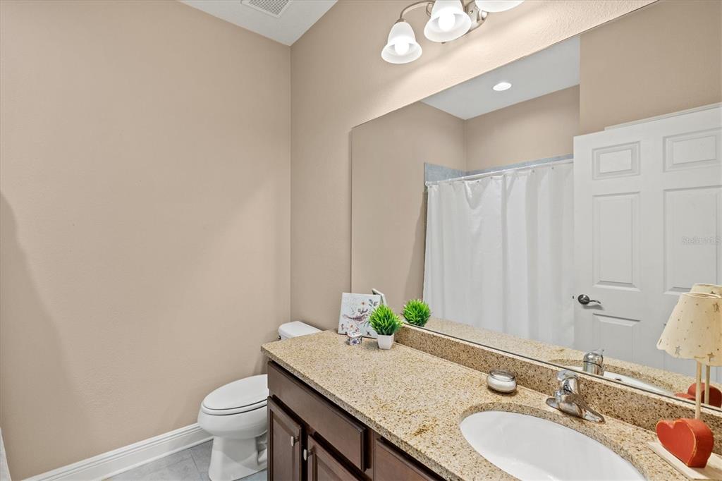 7923 111th Terrace East Parrish, FL 34219 - Photo 30 of 80 a bathroom with a granite countertop sink and a mirror with toilet
