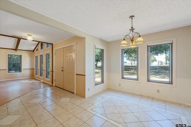 a view of an empty room with window and chandelier fan