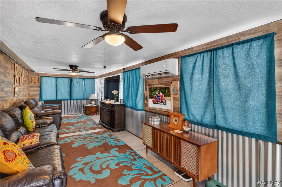 784 Pegasus Ranch Road Bullhead City, AZ 86429 - Photo 51 of 100 Living area featuring two ceiling fans with integrated lighting, wood-finish wall panels, and corrugated metal wainscoting