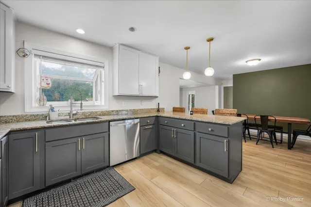 a kitchen with stainless steel appliances granite countertop a sink a stove a dining table and chairs