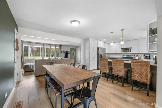 a dining room with stainless steel appliances kitchen island granite countertop a dining table chairs and view of kitchen
